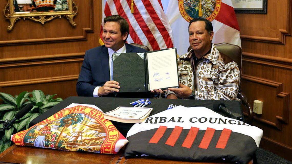 Gov. Ron DeSantis and Marcellus Osceola Jr., chairman of the Seminole Tribe, display the gaming compact that they signed in April.