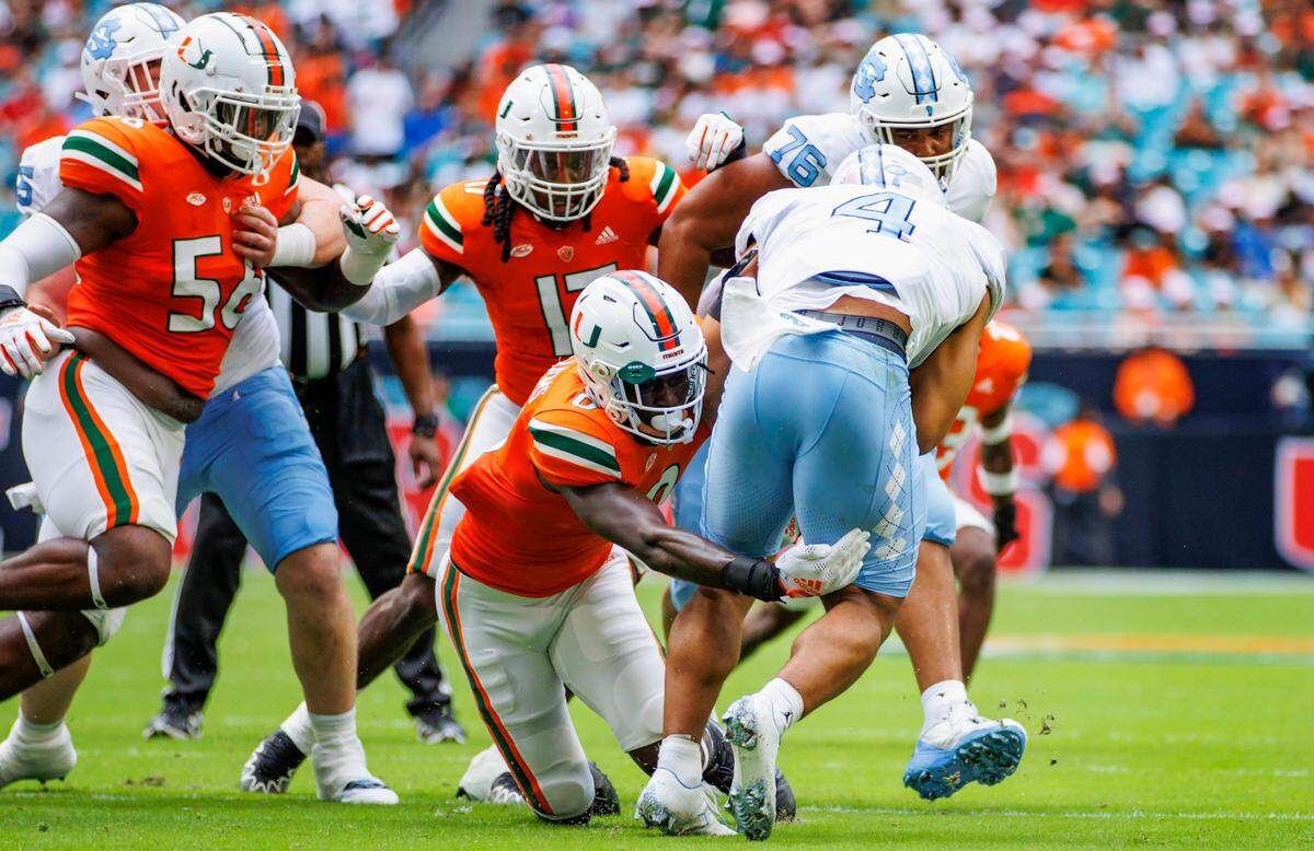 Miami Hurricanes safety James Williams (0) tackles North Carolina Tar Heels running back Caleb Hood (4) during the first quarter of an ACC conference football game at Hard Rock Stadium on Saturday, October 8, 2022 in Miami Gardens, Florida..