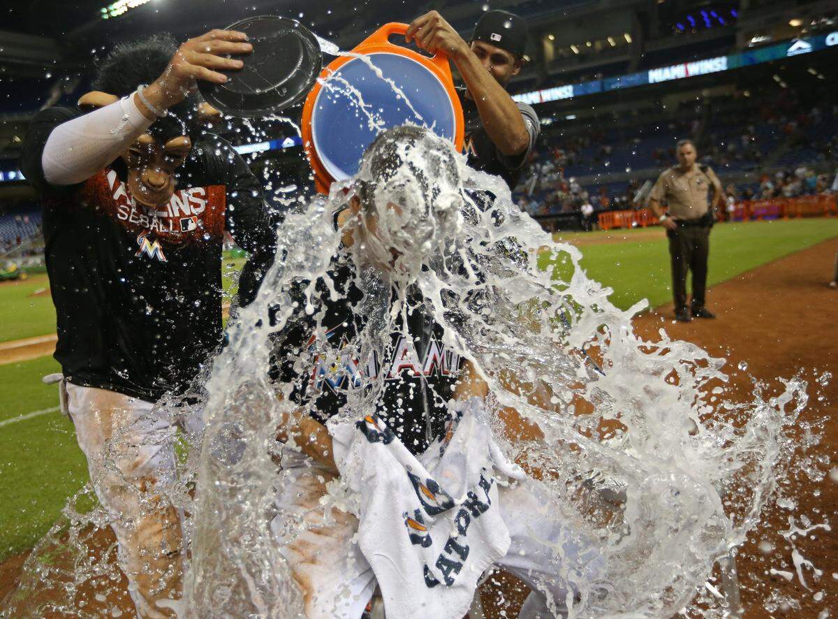 Miami Marlins J.T. Realmuto (11) gets dunked by Miguel Rojas (19), at left, and Yadiel Rivera (2), right, as they celebrate the Marlins win in the tenth inning against the Washington Nationals at Marlins Park on Saturday, July 28, 2018.