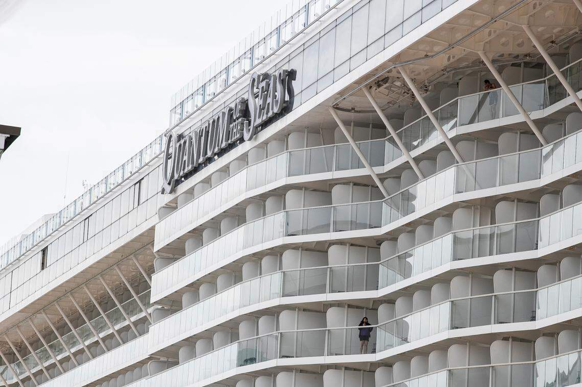 A woman looks out from the balcony of her cabin onboard the Quantum of the Seas cruise ship docked at the Marina Bay Cruise Center Wednesday, Dec. 9, 2020, in Singapore. Royal Caribbean said in a statement that a guest on the Quantum of the Seas “tested positive for coronavirus after checking in with our medical team.” The ship returned to port in accordance with government protocols.