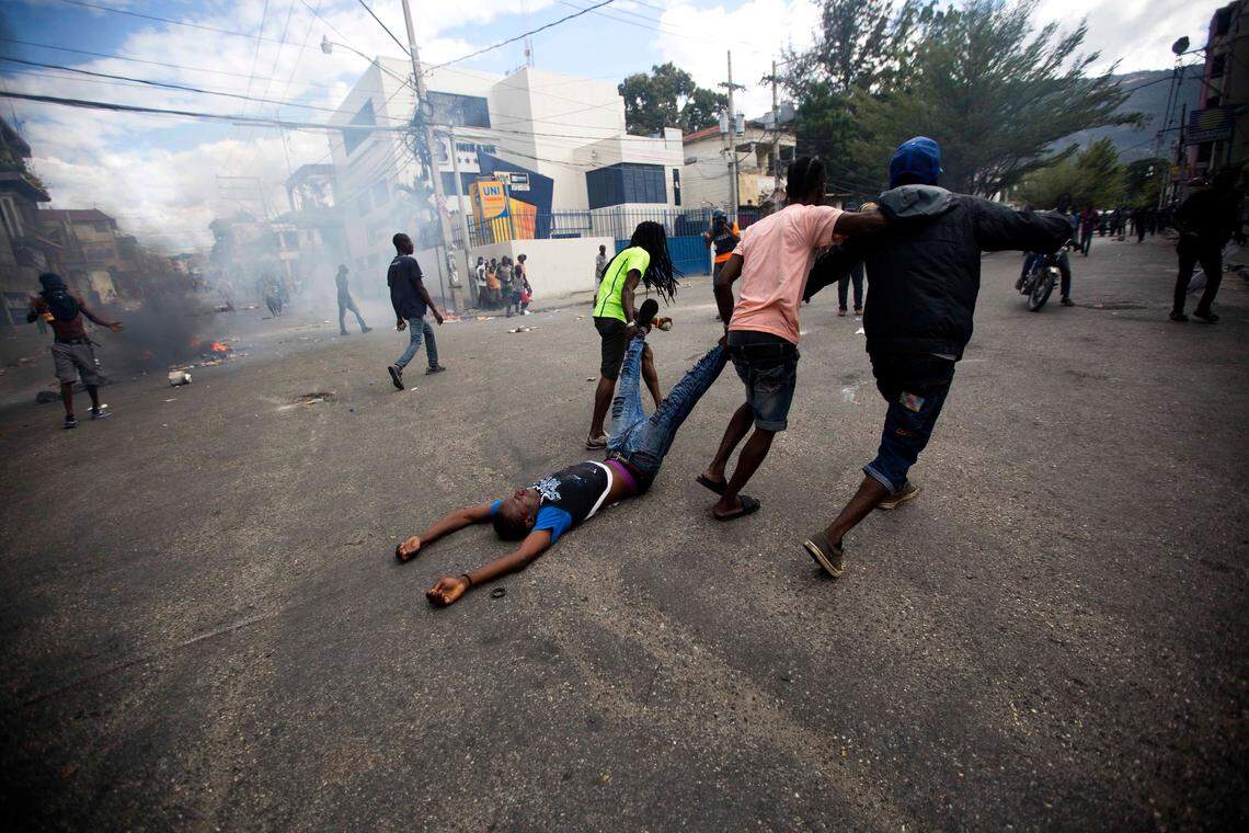 Demonstrators drag the body of a fellow protester toward police, as a form of protest after police shot into the crowd where he died, during a demonstration demanding the resignation of President Jovenel Moise near the presidential palace in Port-au-Prince, Haiti, Tuesday, Feb. 12, 2019. Protesters are angry about skyrocketing inflation and the government’s failure to prosecute embezzlement from a multi-billion Venezuelan program that sent discounted oil to Haiti. (AP Photo/Dieu Nalio Chery)