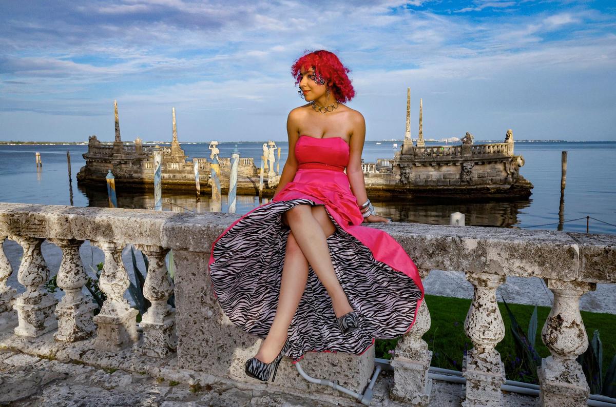 Wearing a prom dress, Ronald W. Reagan/Doral Senior High School’s Flint Nocito, 17, sits on the wall overlooking the bay during Safe Schools South Florida’s prom for queer youth. The event offered students the full prom experience in a welcoming and affirming space at Vizcaya Museum and Gardens in Miami, Florida, on Saturday, May 31, 2025.
