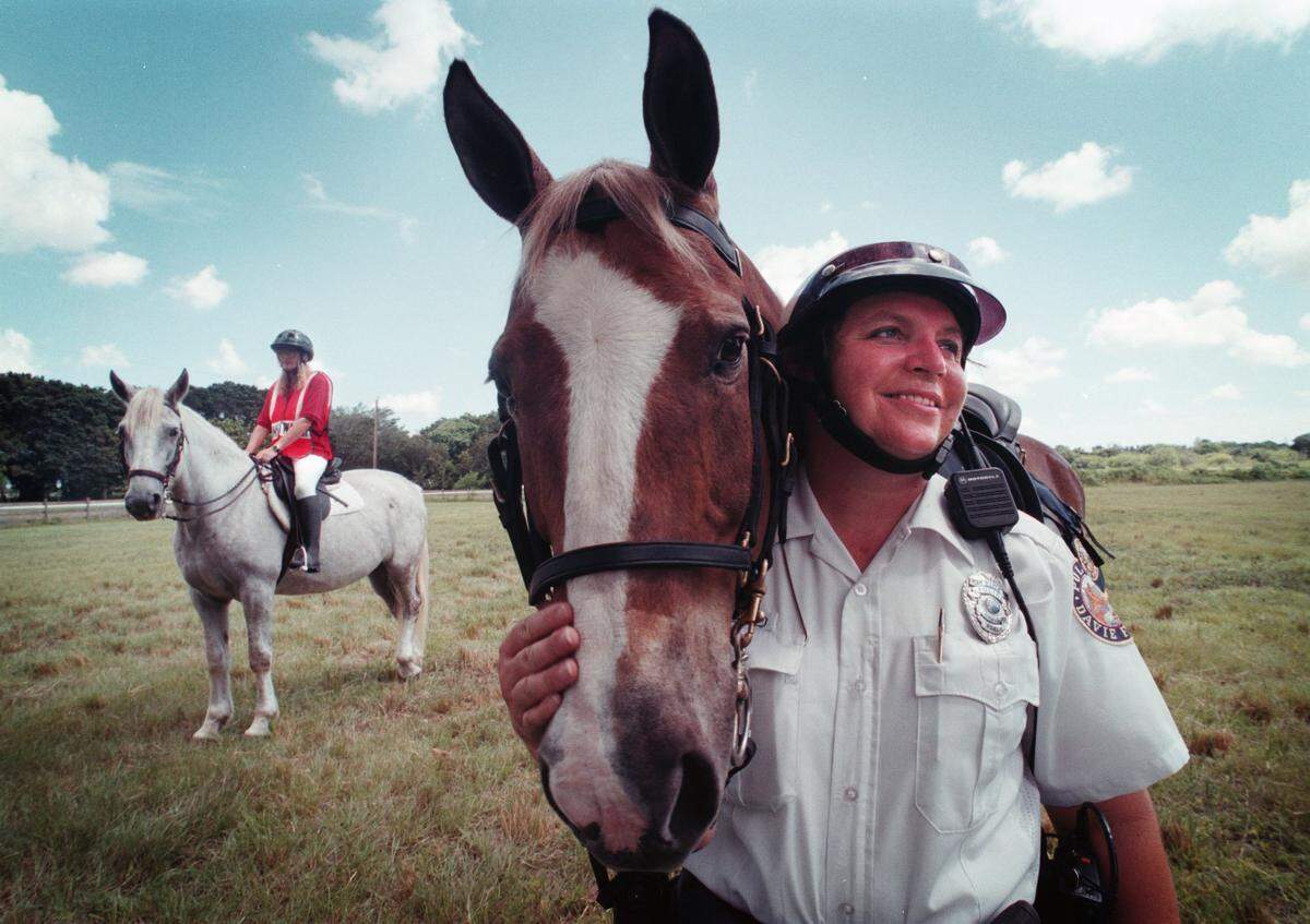 In 2000, Davie Police mounted officer, Kathy Hart, with her police horse, Chocolate, is getting some help patroling horse trails around Davie from a citizen’s mounted patrol. One of the patrol members is Sally Piasecki, pictured in the background with her horse London Fog.