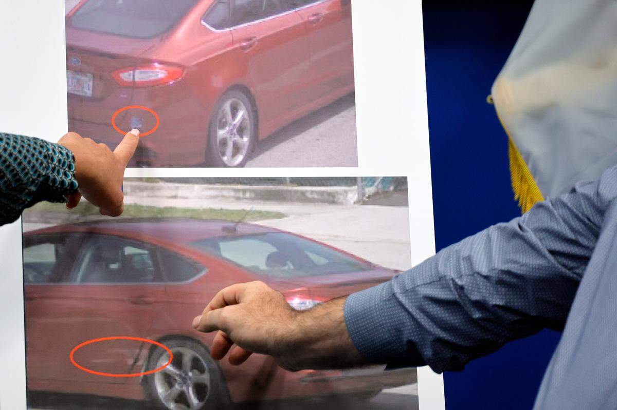 Homicide detective Leann Swisher, left, and homicide Sergeant Donald Geiger point out a sticker, top, and damage, below, on photos of the victims’ vehicle during a news conference in reference to the March 22, 2024, double homicide of Major Melvin, 89, and Claudette Melvin, 85, at their Fort Lauderdale home. This at the Fort Lauderdale Police Department on Wednesday, April 3, 2024.