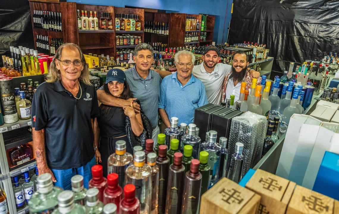 Sunset Corners’ former owners Larry Solomon (far left) and Michael Bittel (third from right), posed with the store’s new owners, from left Nidia and Eduardo Cruz, with their son Kevin Cruz. The Cruzes are the family behind the Jensen’s liquors chain in Miami. Store manager Bruno Barbato (far right), are all pictured at the landmark family business Sunset Corners located at 8701 Sunset Dr., in Miami, on Saturday, June 1, 2024. The new name is Jensen’s at Sunset Corners.
