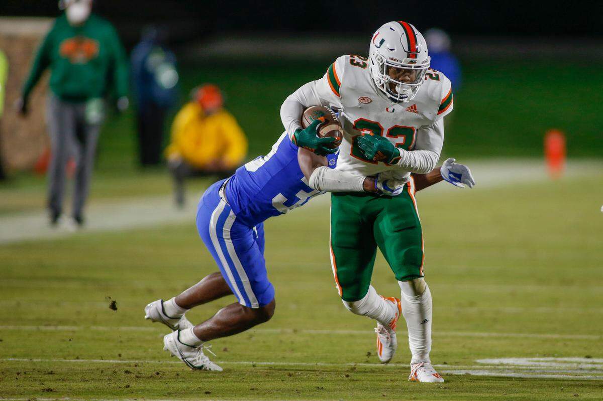 Dec 5, 2020; Durham, North Carolina, USA; Miami Hurricanes running back Cam’Ron Harris (23) fights for yards against Duke Blue Devils cornerback Jeremiah Lewis (left) in the first quarter at Wallace Wade Stadium. Mandatory Credit: Nell Redmond-USA TODAY Sports