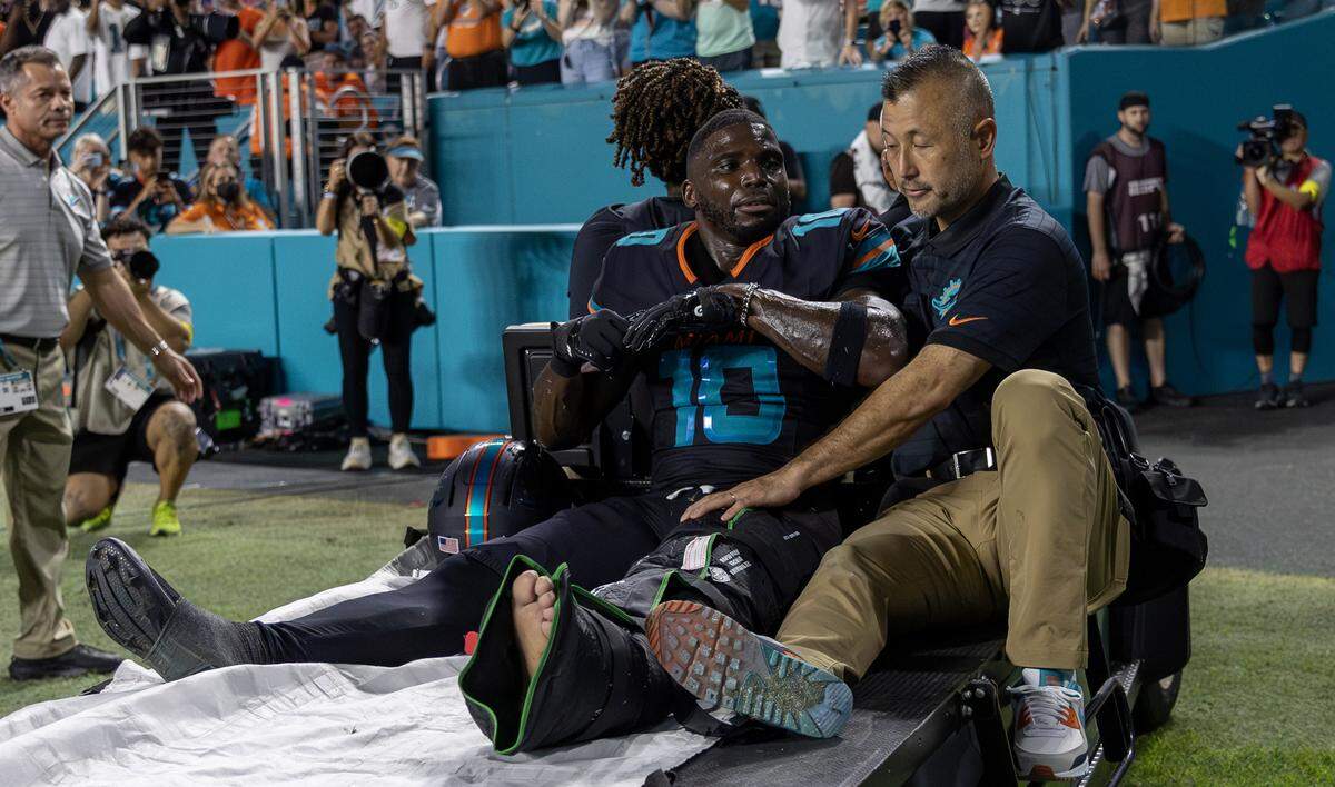 Miami Dolphins wide receiver Tyreek Hill (10) sits next to associate athletic trainer Naohisa Inoue as he is carted off the field after suffering an injury during the second half of an NFL game against the New York Jets at Hard Rock Stadium on Monday, Sept. 29, 2025, in Miami Gardens, Fla.