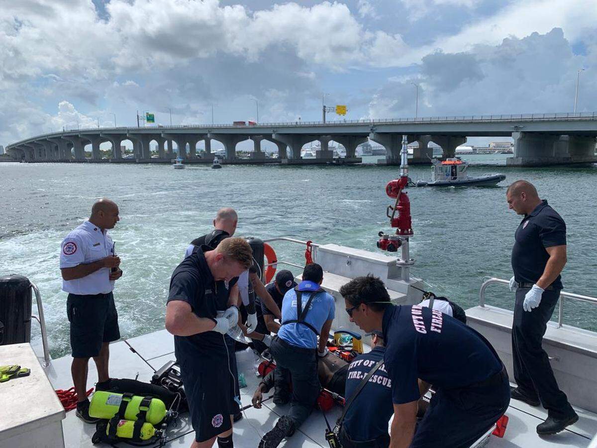 Miami Fire Rescue workers keep the man who jumped off the MacArthur Causeway Monday alive after pulling him out of Biscayne Bay.