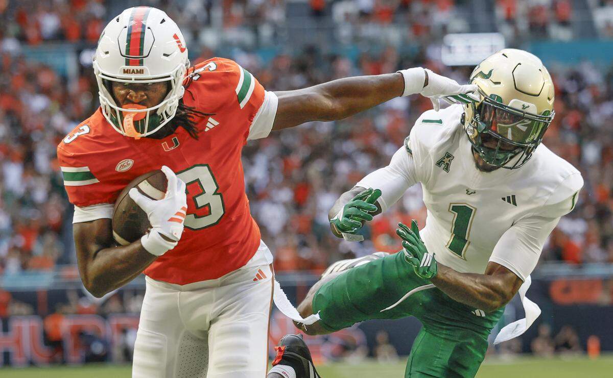 Miami Hurricanes wide receiver Joshua Moore (3) sores as South Florida Bulls cornerback Ben Knox (1) defends in the first half of their NCAA football game at Hard Rock Stadium in Miami Gardens, Florida, on Saturday, September 13, 2025.