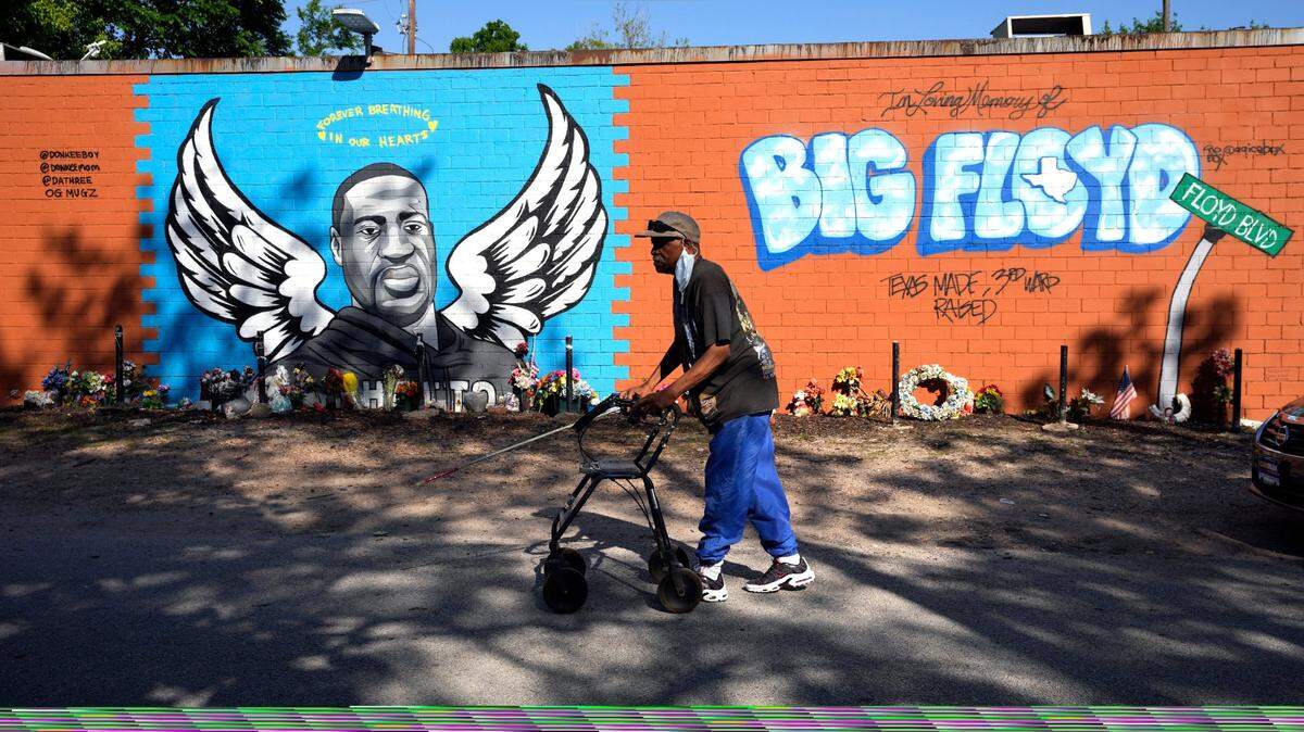 Ronaly Brooks camina frente a un mural de George Floyd en el vecindario donde creció Floyd, el martes 20 de abril de 2021, en Houston.