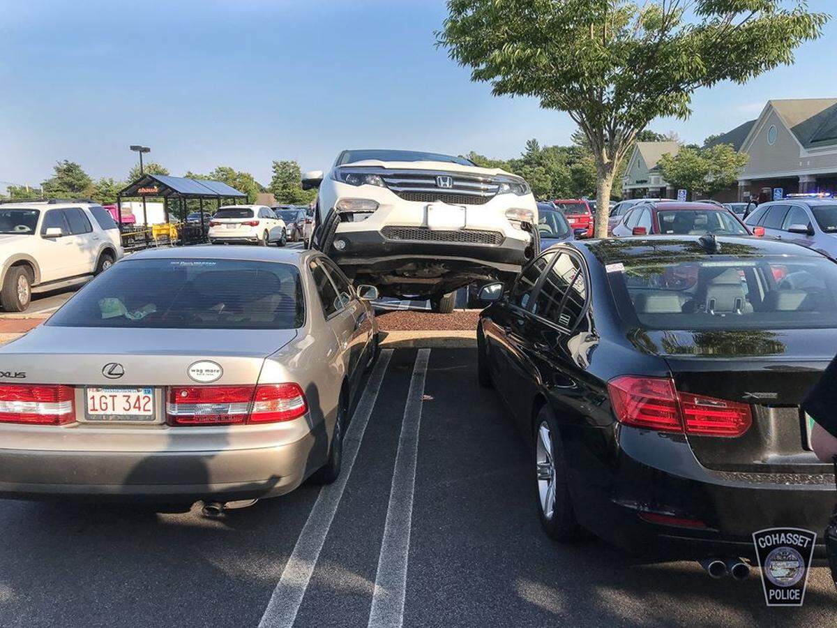 The front wheels of the car straddled two other parked cars.