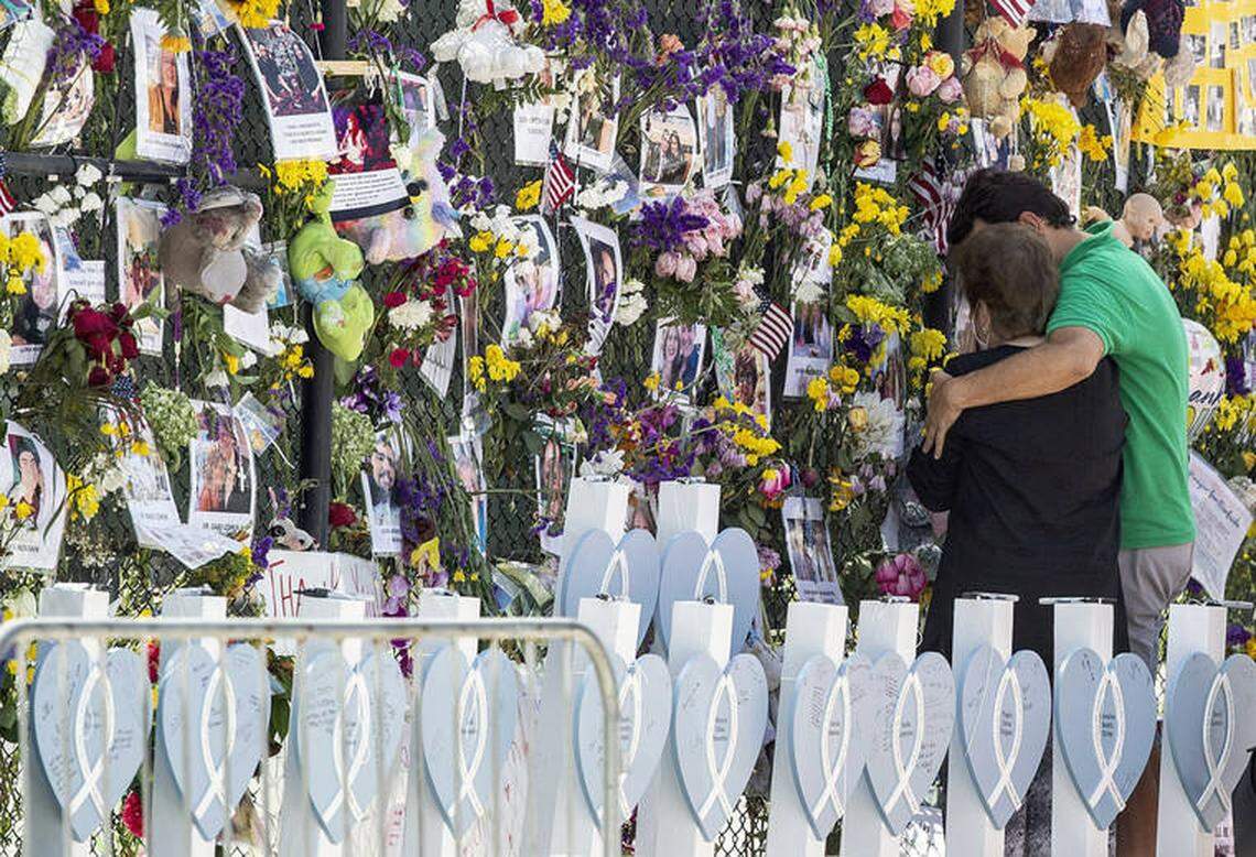 People stand at the memorial wall at the site of the deadly condo collapse of Champlain Towers South in Surfside.
