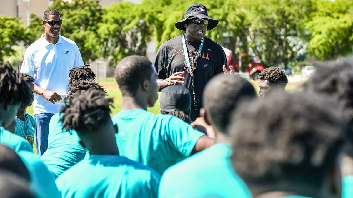 Miami Dolphins Youth Programs Ambassador Twan Russell (left) and Booker T. Washington coach Tim ‘Ice’ Harris talk to Booker T players.