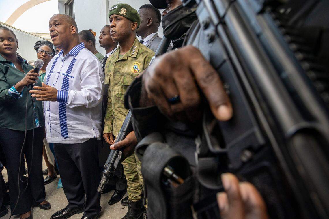 A police officer keeps his trigger finger at the ready as then-Haitian Prime Minister Gary Conille, left, speaks to the press along with Haiti Police Chief Rameau Normil, right, at Hospital Bernard Mevs in August.