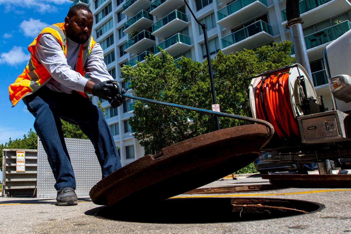 Stormwater Operator Jelanie Rouland opens a manhole near 10th Street and West Avenue in Miami Beach on Wednesday, May 25, 2022.