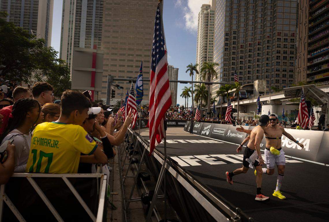 Two men give each other pats on the back as they come down the final marathon stretch during the Life Time Miami Marathon and Half on Sunday, Jan. 28, 2024, finishing at Bayfront Park in downtown Miami.