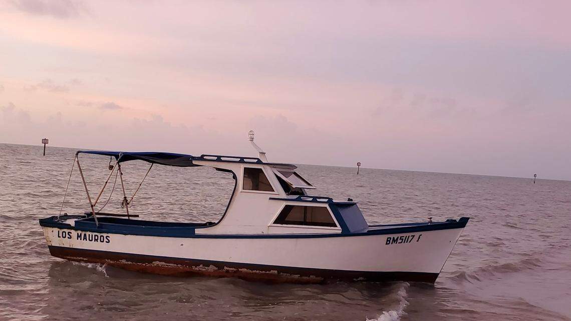 A wooden fishing boat rests in the shallow water on the shore of Key West Saturday, Dec. 18, 2021. The boat, along with another fishing vessel, carried 37 migrants from Cuba, according to the U.S. Border Patrol.