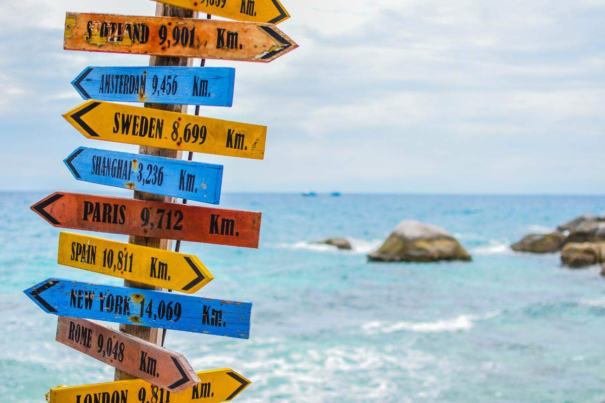 wooden beach sign with city names