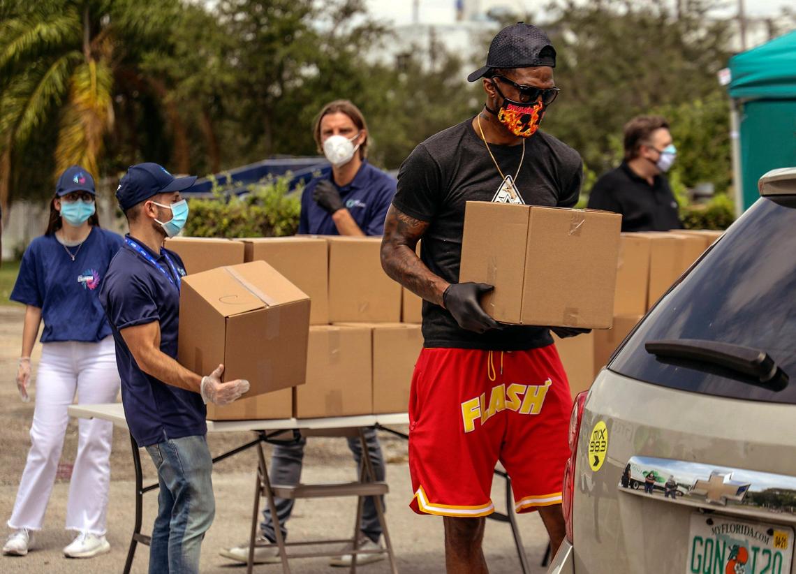Miami Heat forward Udonis Haslem, right, carries a box of groceries as part of Stock-Up Mart, a new grocery delivery service powered by Miami-based REEF Technology. They have teamed up with Haslem and Miami City Commissioner Ken Russell to donate a week’s worth of groceries to 100 families in need via a drive-through event in the Omni/Edgewater neighborhood on Wednesday, May 13, 2020.