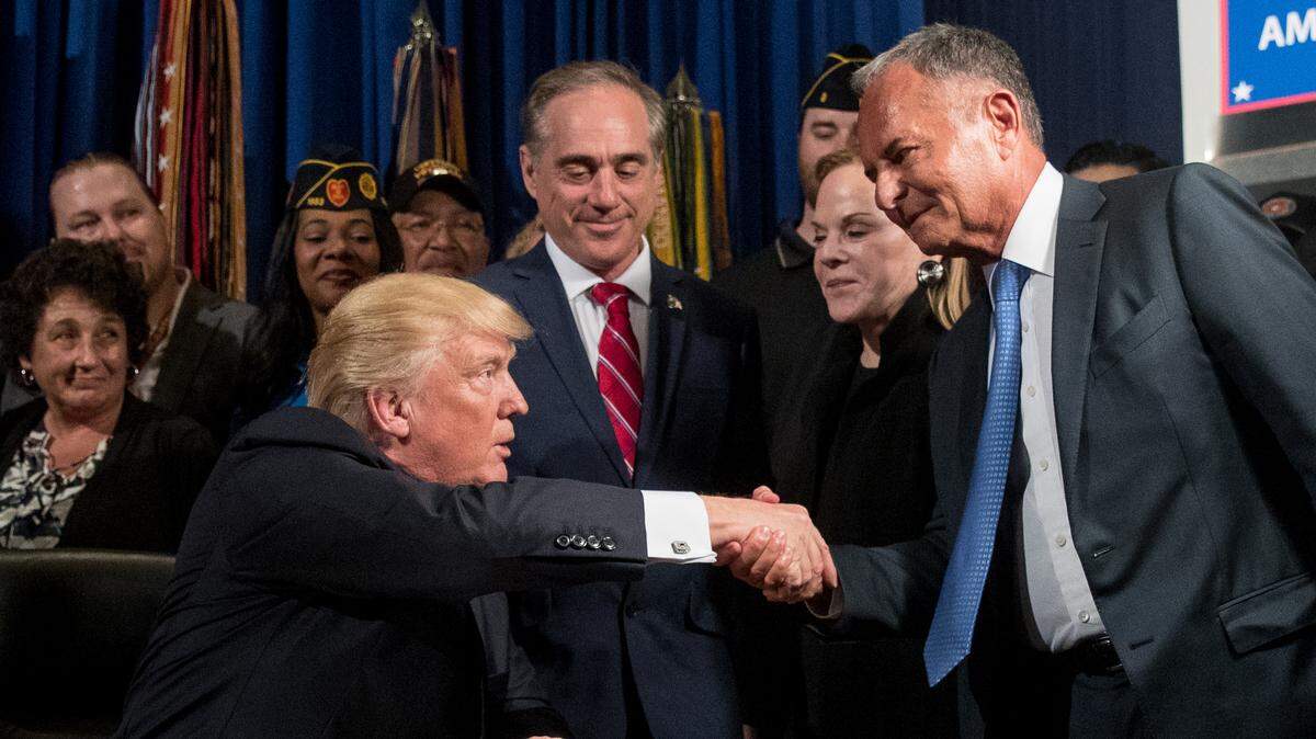 President Donald Trump, left, accompanied by Veterans Affairs Secretary David Shulkin, center, shakes hands with Isaac “Ike” Perlmutter, the chairman Marvel before signing an Executive Order at the Department of Veterans Affairs, April 27, 2017, in Washington. Also pictured is Laura Perlmutter, second from right.