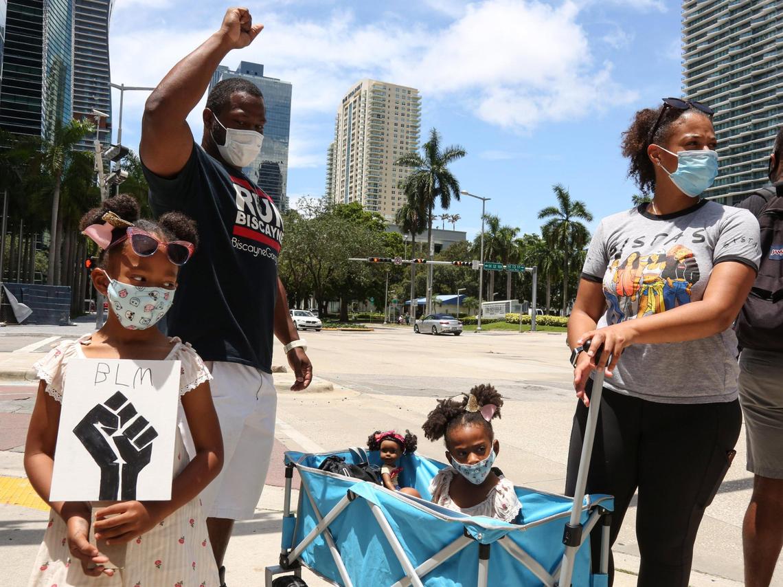 Ashley Hurst, right, and Rickman Johnson, raising his fist, are seen at a rally with their two daughters, Destiny, front, and Desiree, center, during a rally in the neighborhood of Brickell in Miami, Saturday, June 13, 2020.