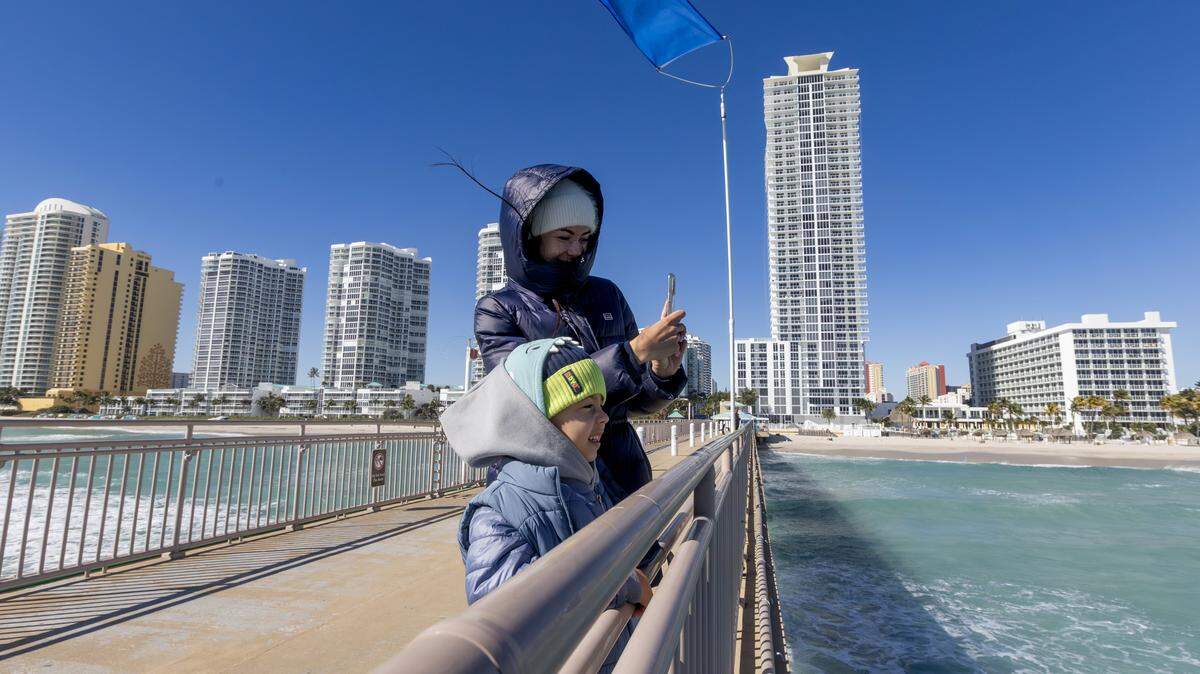 Anna Lysova takes photos with her son, Myron. They were bundled against the cold at the Newport Fishing Pier in Sunny Isles Beach, Fla., on Sunday, Feb. 1, 2026. Miami-area temperatures dipped into the 30s at the time. The forecast for the week beginning Feb. 9 calls for mornings in the 50s and 60s and afternoons in the mid- to upper-70s.