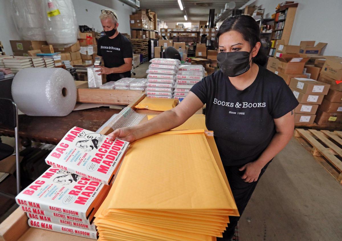 Books & Books employee Ana Guerra packs books in envelopes as she fulfills holiday orders that are shipping out of the company warehouse on Thursday, December 17, 2020.