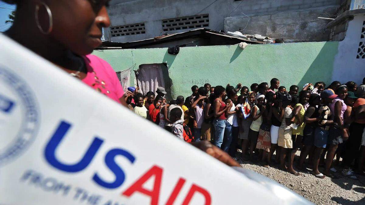 People wait at a USAID distribution point for help after the 2010 earthquake in Haiti.
