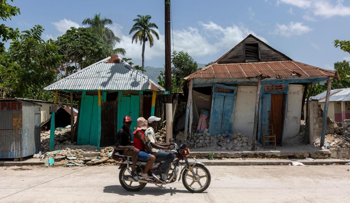 Men ride by homes in Maniche, Haiti, on Monday, Aug. 23, 2021. The houses were damaged during the Aug. 14, 2021, earthquake.