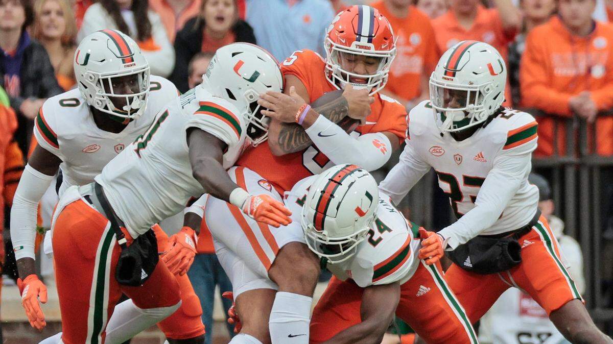 Miami Hurricanes linebacker Wesley Bissainthe (31), safety Kamren Kinchens (24), and cornerback Te’Cory Couch (23) gang tackle quarterback DJ Uiagalelei (5) in the first half at Frank Howard Field at Clemson Memorial Stadium in Clemson, South Carolina on Saturday, November 19, 2022.