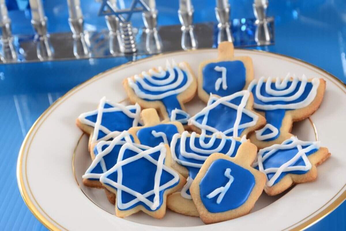A plate of homemade sugar cookies for Hanukkah —&nbsp;dreidels, stars, and menorahs.