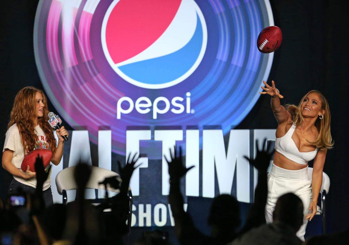Shakira looks as Jennifer Lopez throws a football during press conference for the halftime show on Sunday during Super Bowl LIV at Hard Rock Stadium at Hilton Miami Downtown on Wednesday, Jan. 30, 2020 in Miami.