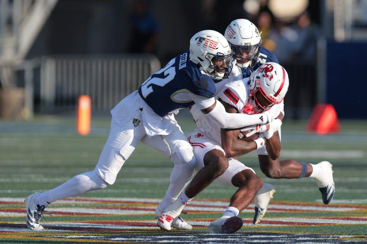 FIU Panthers defensive back Shamir Sterlin (22) qndFIU Panthers defensive back Mister Clark (27) tackle Jacksonville State Gamecocks wide receiver Deondre Johnson (11) during the first quarter at Pitbull Stadium on Saturday, Nov. 22, in Miami, Fla.