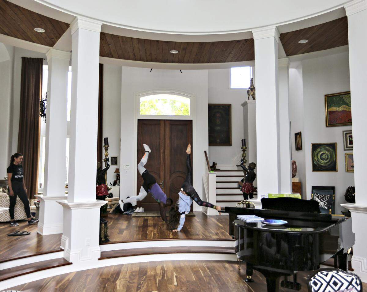 Palm Beach socialite and former model, Margaret Luce, left, and her family have been trying to deal with the anxiety over Hurricane Dorian for the last several days. Margaret watches as her workout partner, Maurice Nunes, center, and her daughter, Claire Luce, 12, right, perform handstands inside her home while waiting for the latest news regarding Hurricane Dorian as it moved slowly on a northern track about 100 miles off of Palm Beach, Florida on Tuesday, September 3, 2019.