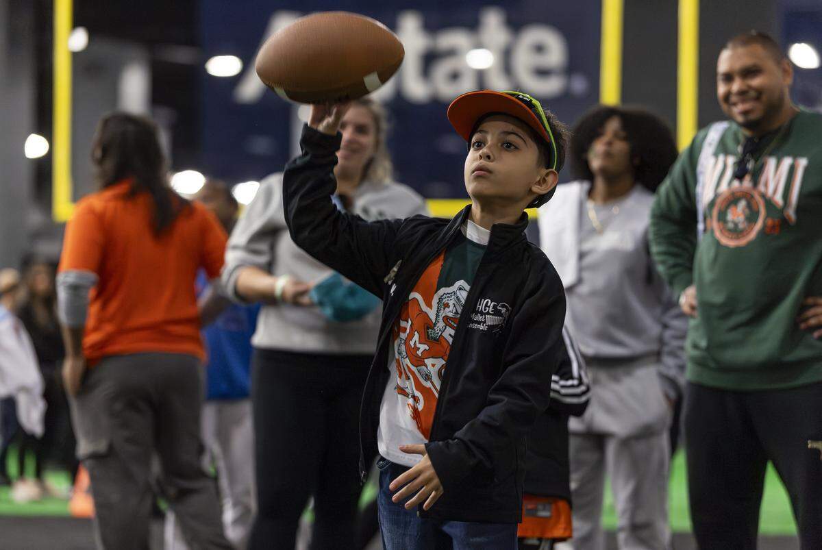 Aiden Villafañe, 9, throws a football while visiting the Playoff Fan Central at the Miami Beach Convention Center on Friday, Jan. 16, 2025, in Miami Beach, Fla. Fans can visit the event ahead of the College Football Playoff National Championship Game between the Miami Hurricanes and the Indiana Hoosiers and enjoy a variety of family-friendly interactive experiences.