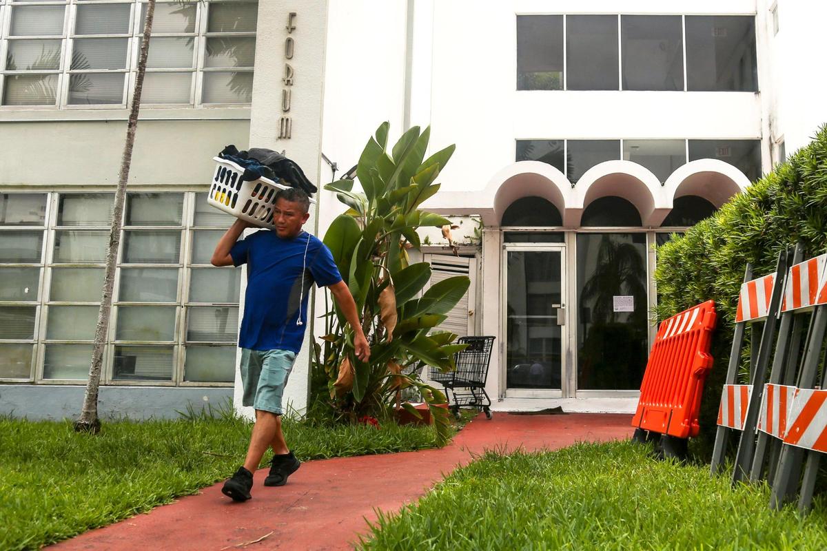 Hector Mendez carries some personal items in a basket out of the front entrance of the Forum building on 1080 93rd Street in Bay Harbor Islands, Florida, after city officials deemed the building to be unsafe on Wednesday, Sept. 1, 2021.