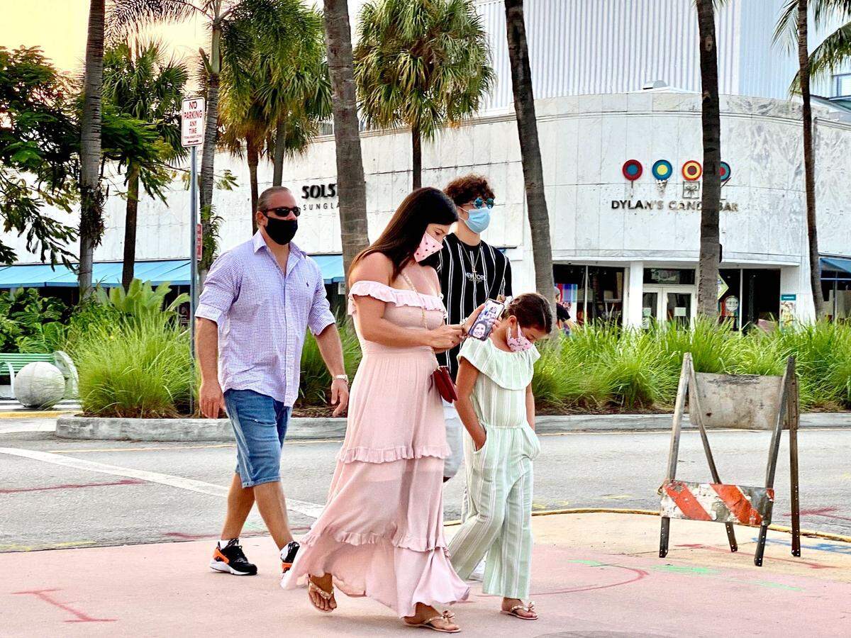 A family strolls Lincoln Road in Miami Beach in masks, which are mandatory in Miami-Dade County.