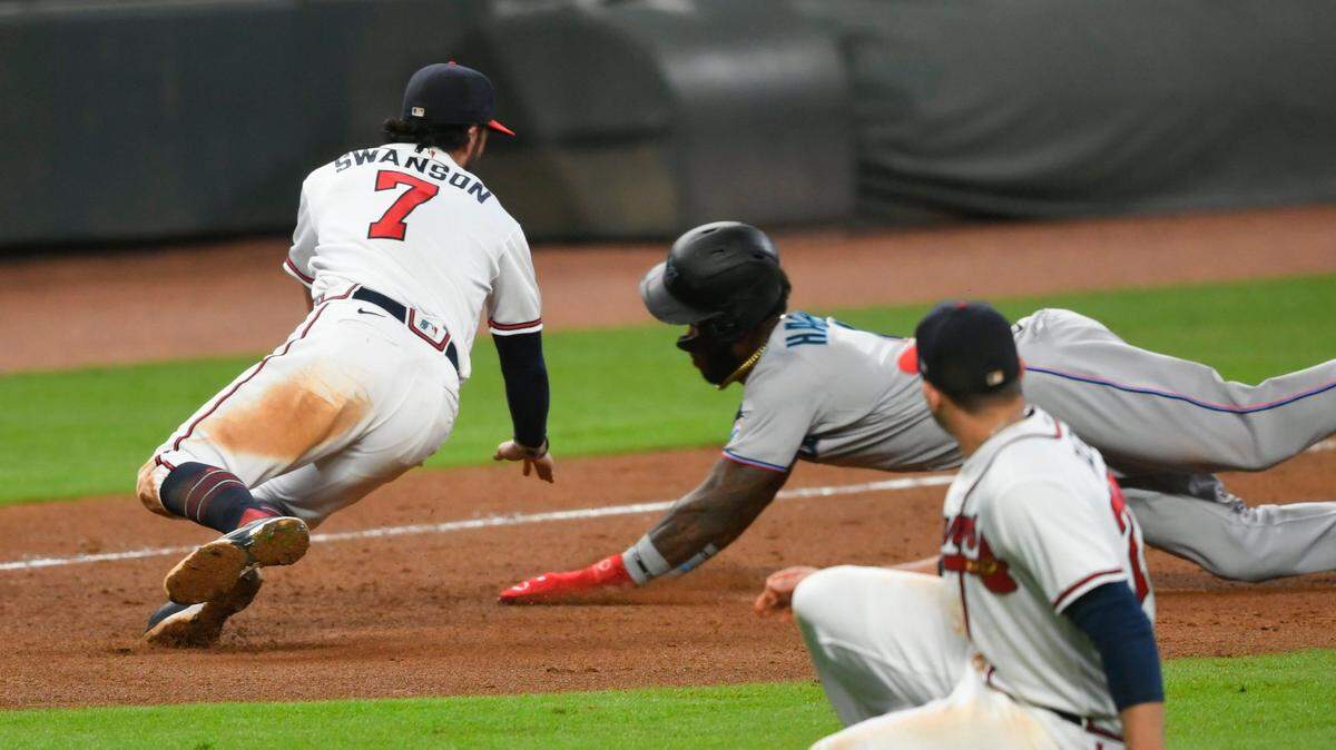 Atlanta Braves shortstop Dansby Swanson (7) moves in to tag out Miami Marlins’ Monte Harrison, back right, at third base for a double play on a throw from first baseman Freddie Freeman as Braves relief pitcher Mark Melancon ducks in the foreground during the ninth inning of a baseball game Monday, Sept. 21, 2020, in Atlanta. (AP Photo/John Amis)