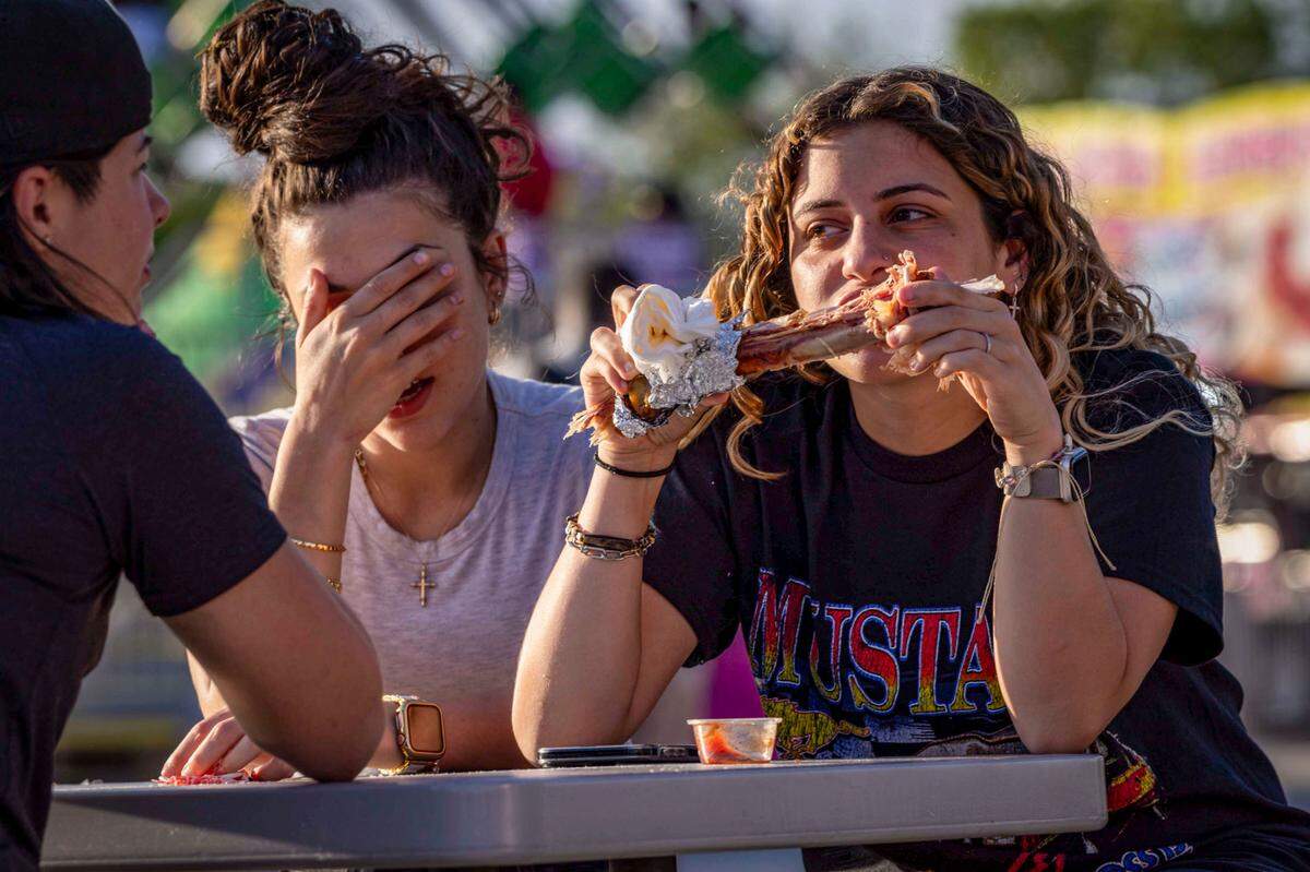 A fairgoer munches on a turkey leg during the first day of the Miami-Dade County Fair & Exposition