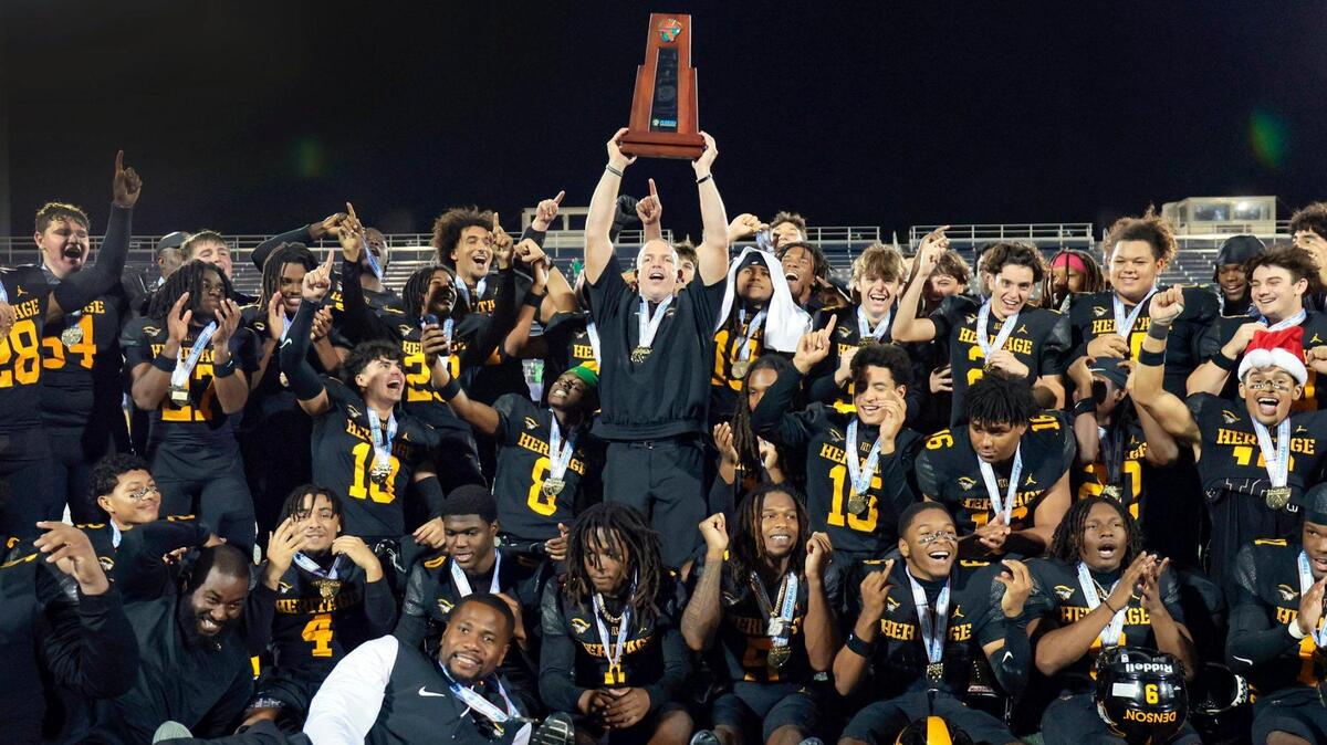 American Heritage coach Mike Smith raises the championship trophy after defeating Jones High School in the Florida High School Football State Championships - Class 4A game at Pitbull Stadium on the campus of Florida International University in Miami, Florida, on Friday, December 13, 2024.