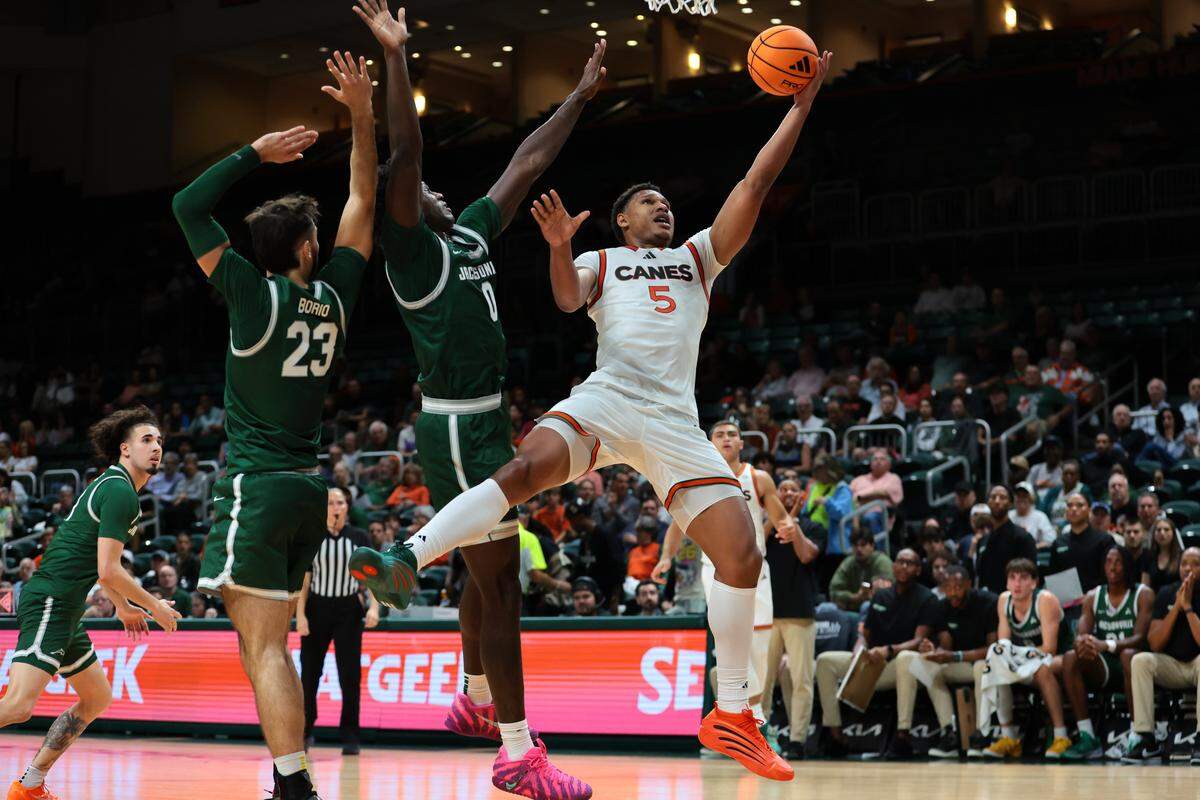 Miami Hurricanes forward Malik Reneau (5) drives to the basket against Jacksonville Dolphins forward Jaylen Jordon (0) and forward Enrico Borio (23) during the first half at Watsco Center, in Coral Gables, Florida, Monday, November 3, 2025.