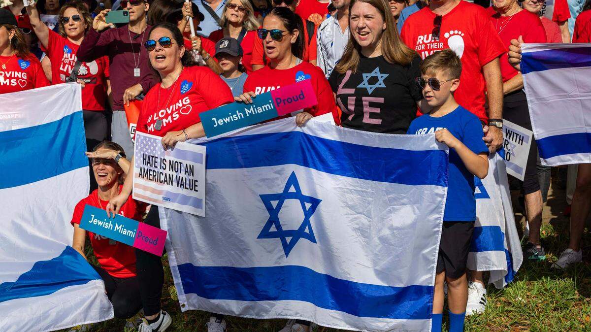Manifestantes sostienen banderas israelíes y carteles que dicen “EL ODIO NO ES UN VALOR ESTADOUNIDENSE” durante la caminata solidaria de Run for Their Lives para crear conciencia sobre los 58 rehenes que aún permanecen retenidos en Gaza, en Aventura Circle el domingo 8 de junio de 2025, en Aventura, Florida.
