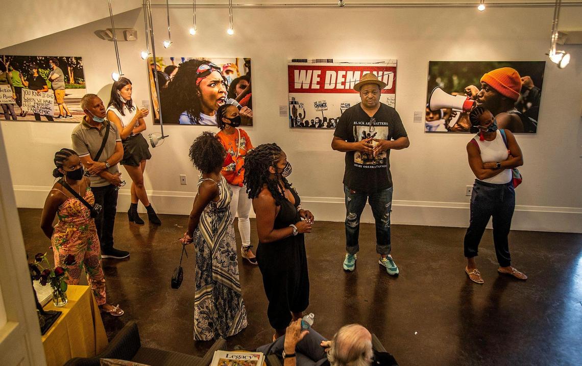 Christopher Norwood (second from right), co-founder of Hampton Art Lovers, guides a group of visitors through the exhibit “To Miami, with Love”: Pandemic Life and Protest,” by photographer Rahsaan Alexander, at the Historic Ward Rooming House in Miami’s Overtown neighborhood in April.