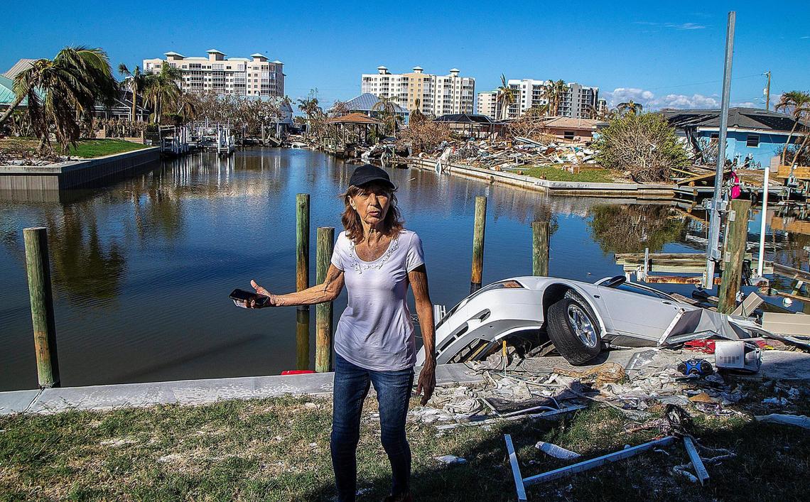 Fort Myers Beach resident JoAnn Knobloch stands next to her 2003 Ford Mustang that hangs off the seawall behind her Estero Boulevard house Wednesday, Oct. 26, 2022. Knobloch’s husband drowned in Hurricane Ian’s storm surge a month earlier.