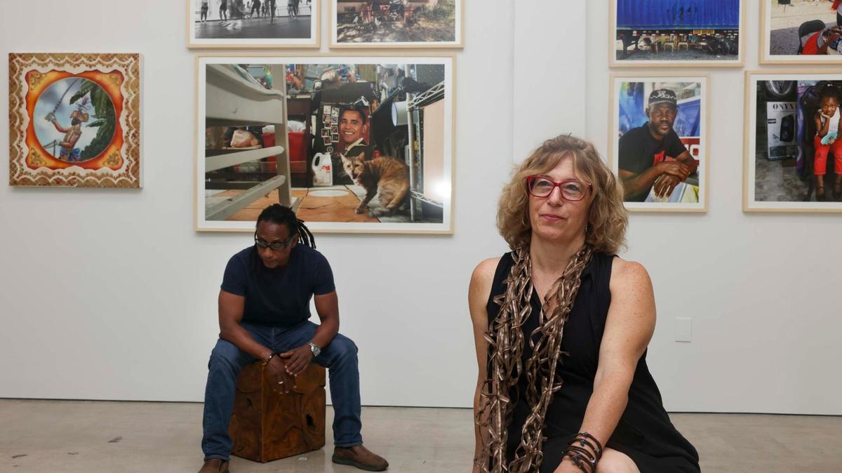 Rebecca Friedman, right, and Carl-Philippe Juste pose in front of photographs taken by locals during a photo walk in Little Haiti that the two selected while curating the ‘I am Haiti’ exhibit on Thursday, May 9, 2024, at Green Space Miami in Little Haiti. The exhibit is composed of photographs, paintings, and memorabilia from locally based artists.