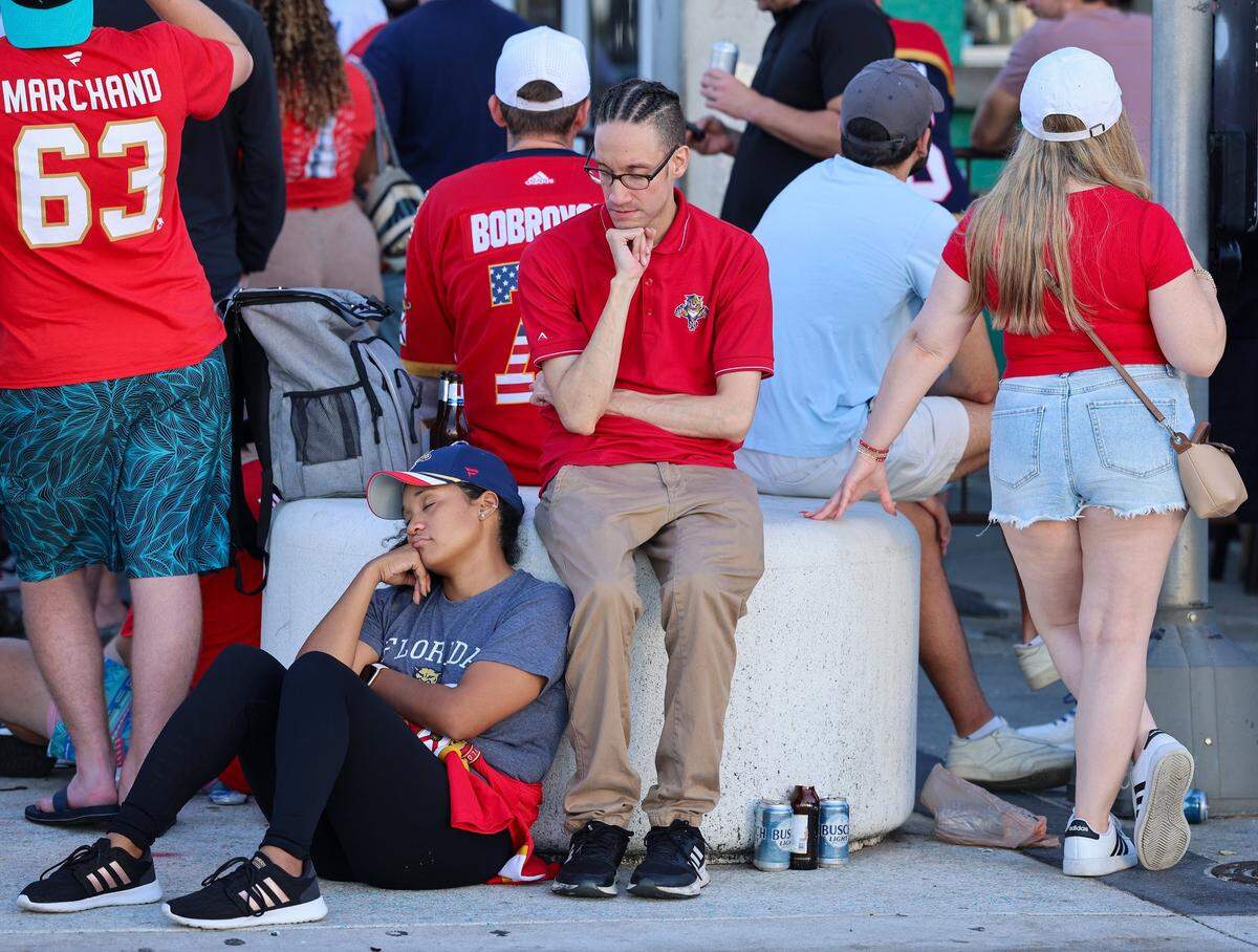 A Panthers fan, left, take a quick nap as she and others wait outside the Elbo Room in Fort Lauderdale before sunrise the day after the Florida Panthers won the Stanley Cup Final for the second time on Wednesday, June 18, 2025.