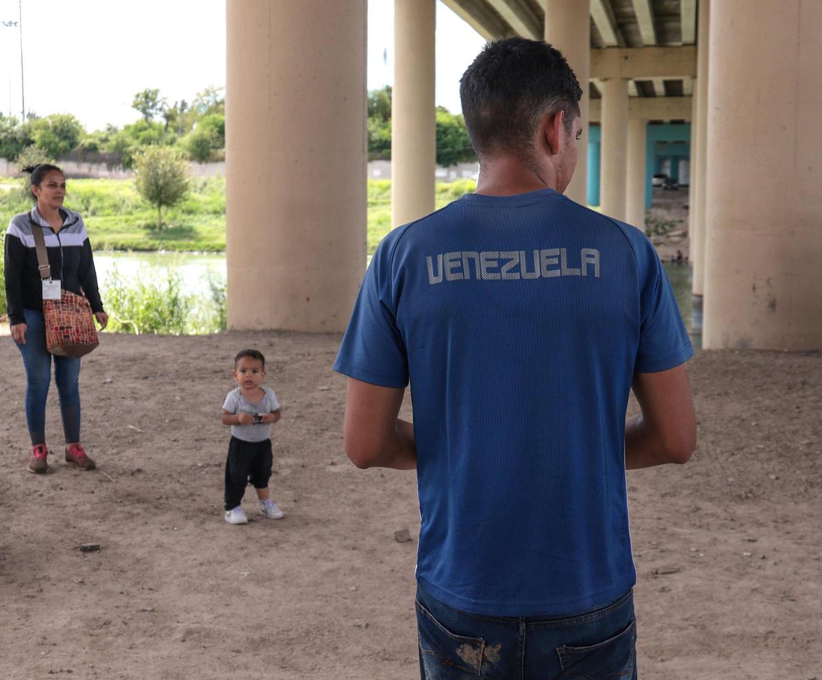 Migrantes venezolanos esperan la llegada de la Patrulla Fronteriza de Estados Unidos tras cruzar el Río Grande.