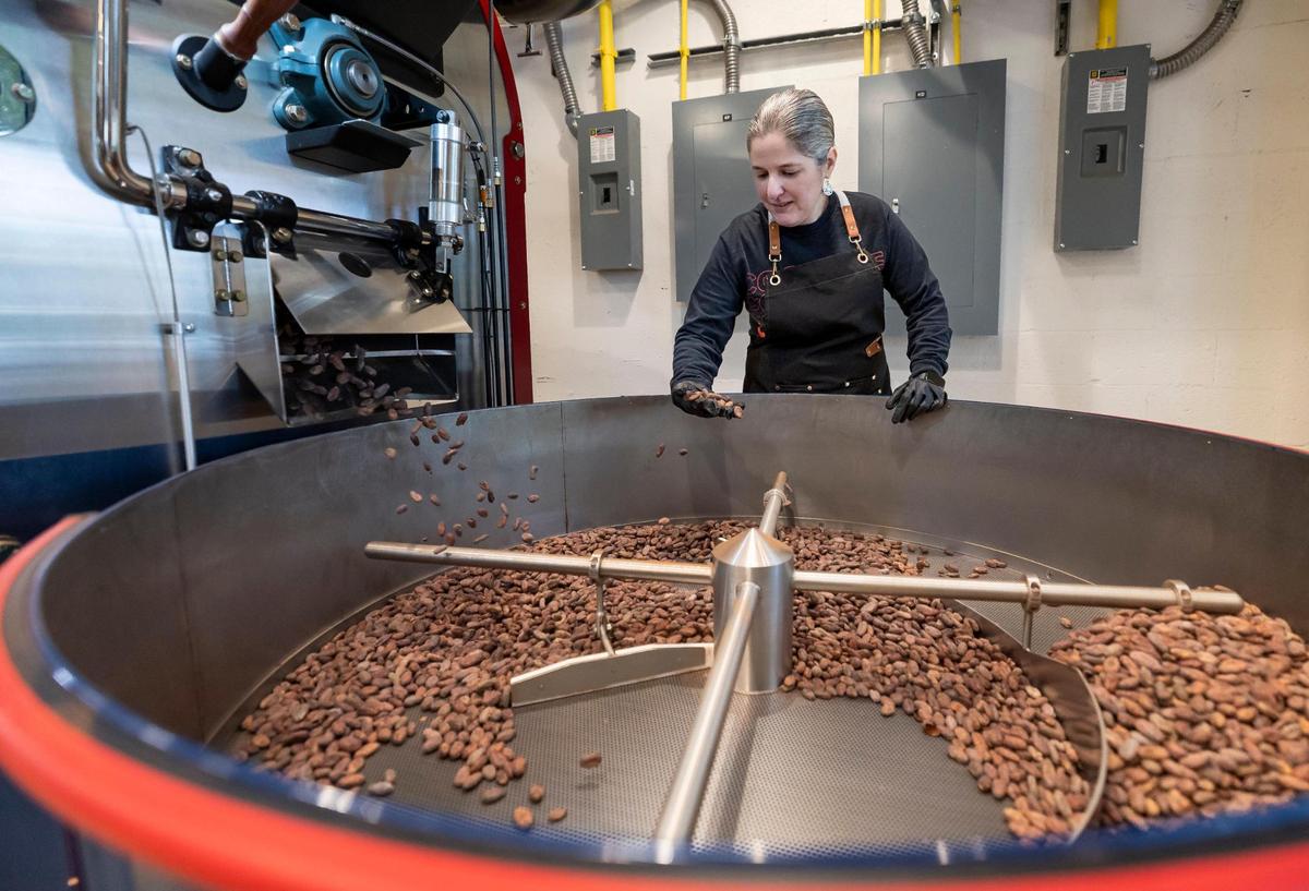Carolina Quijano, founder of Exquisito Chocolates, inspects a batch of cacao beans as they come out of a repurposed coffee roaster at her new factory on Calle Ocho.