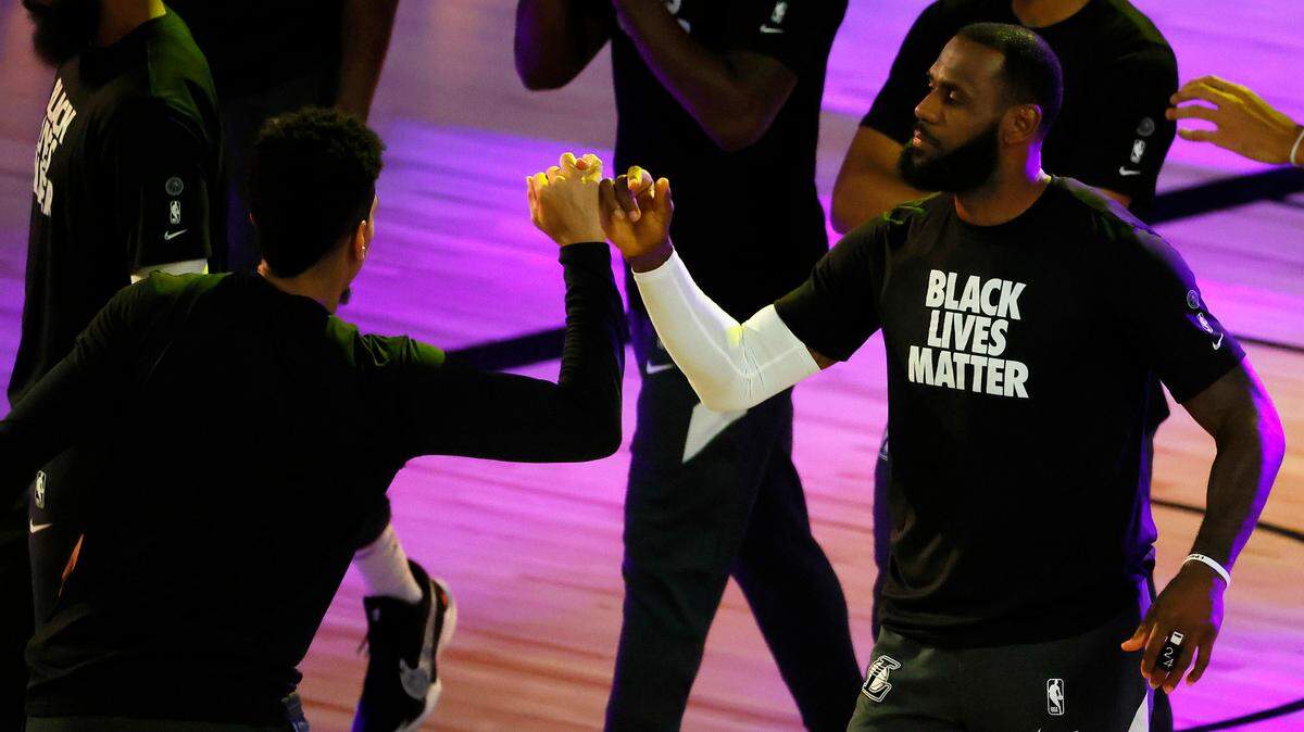 Los Angeles Lakers’ Danny Green, left, and LeBron James #23 and Danny Green lock pinkie fingers during player introductions before an NBA basketball game against the Sacramento Kings Thursday, Aug. 13, 2020, in Lake Buena Vista, Fla.