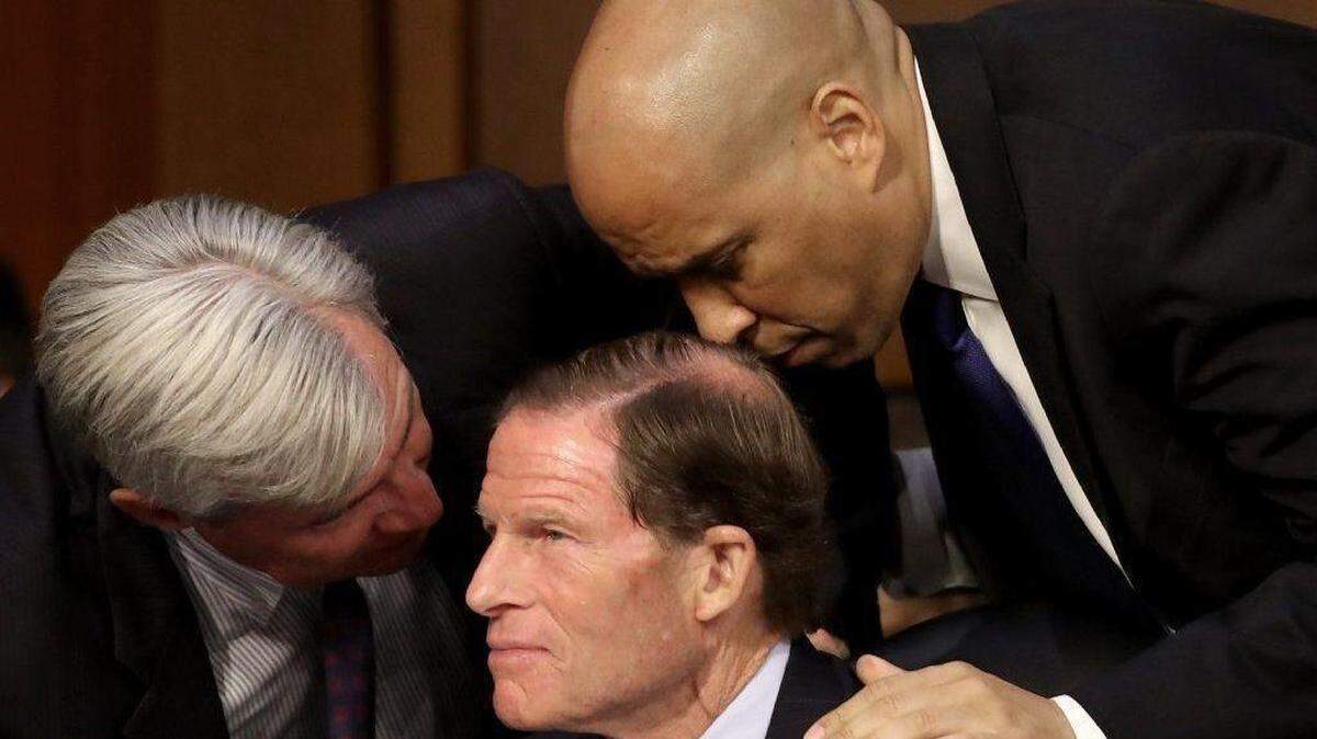 Democratic Sens. Sheldon Whitehouse, Richard Blumenthal and Cory Booker, left to right, huddle as Supreme Court nominee Brett Kavanaugh appears before the Senate Judiciary Committee.
